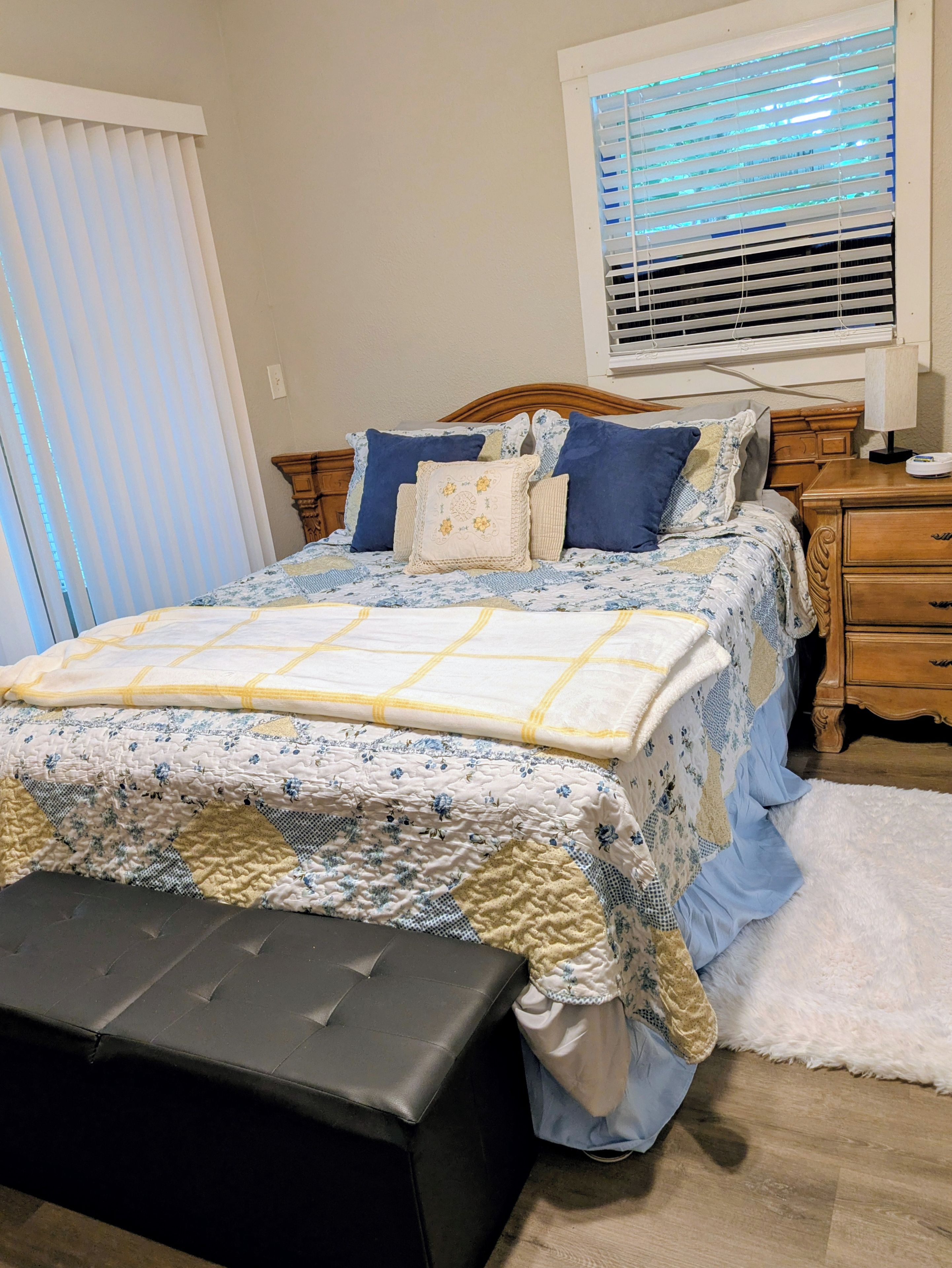A bedroom with a bed, bedside tables, a window with blinds, and a bench.