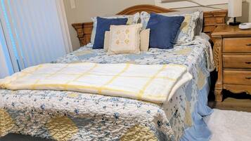 A bedroom with a bed, bedside tables, a window with blinds, and a bench.