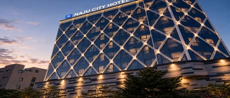 A modern hotel building with a distinctive geometric facade and illuminated signage.