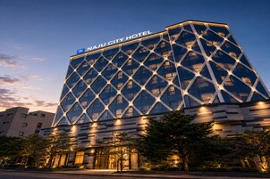 Edifício de hotel moderno com fachada geométrica marcante e sinalização iluminada.