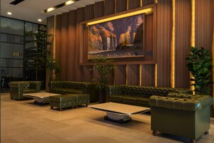 Um hall com sofás de couro, uma mesa de centro e uma pintura grande na parede.
