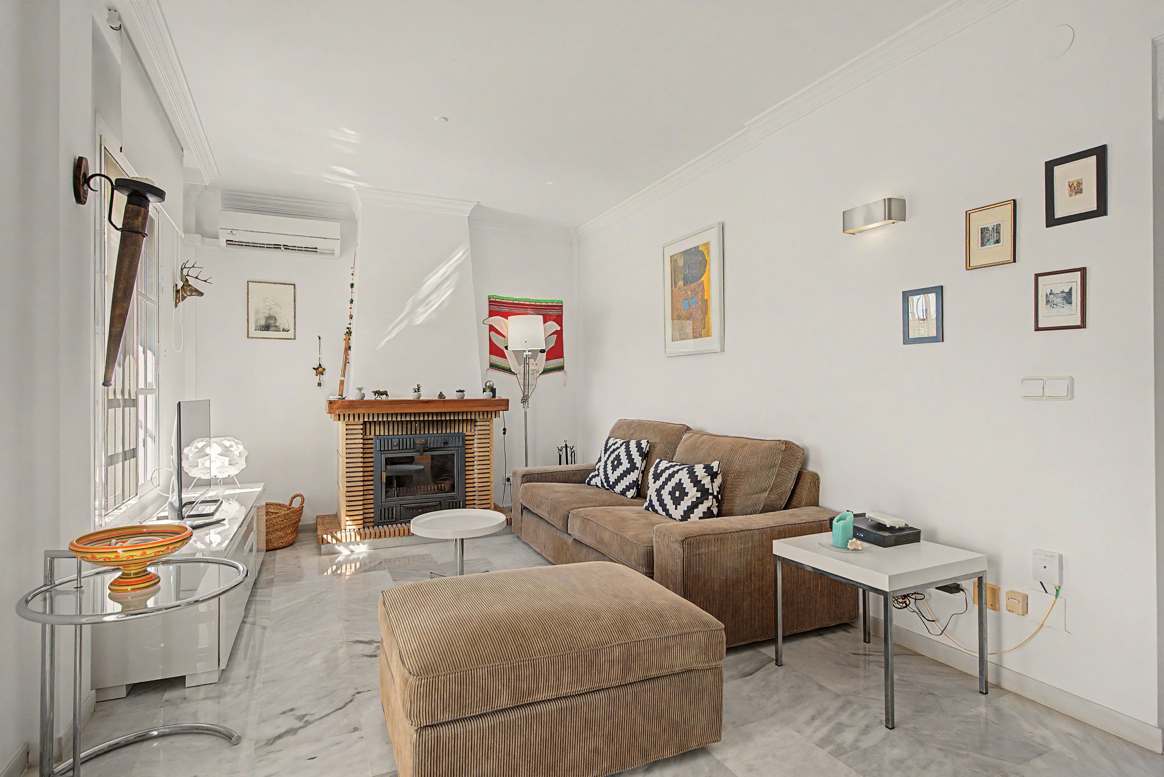 Una sala de estar con chimenea, un sofá, una mesa de centro y un mueble para televisor.