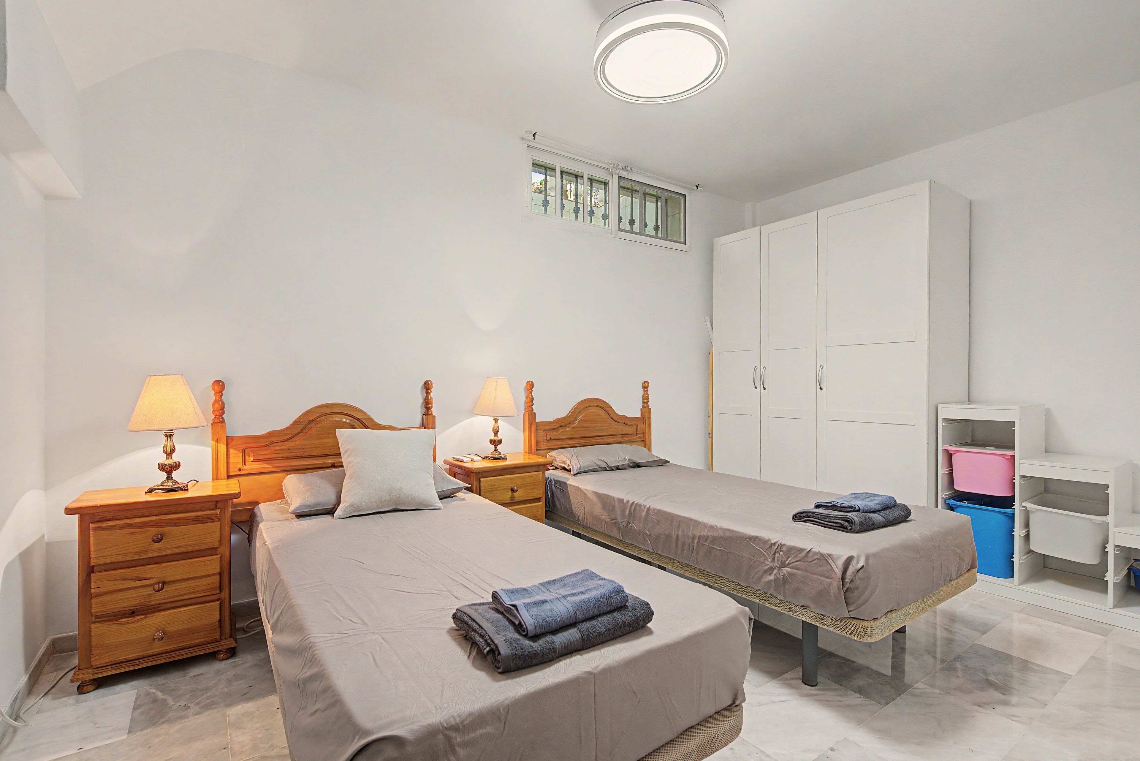 Een hotelkamer met twee bedden, een kast, een bureau en een lamp.