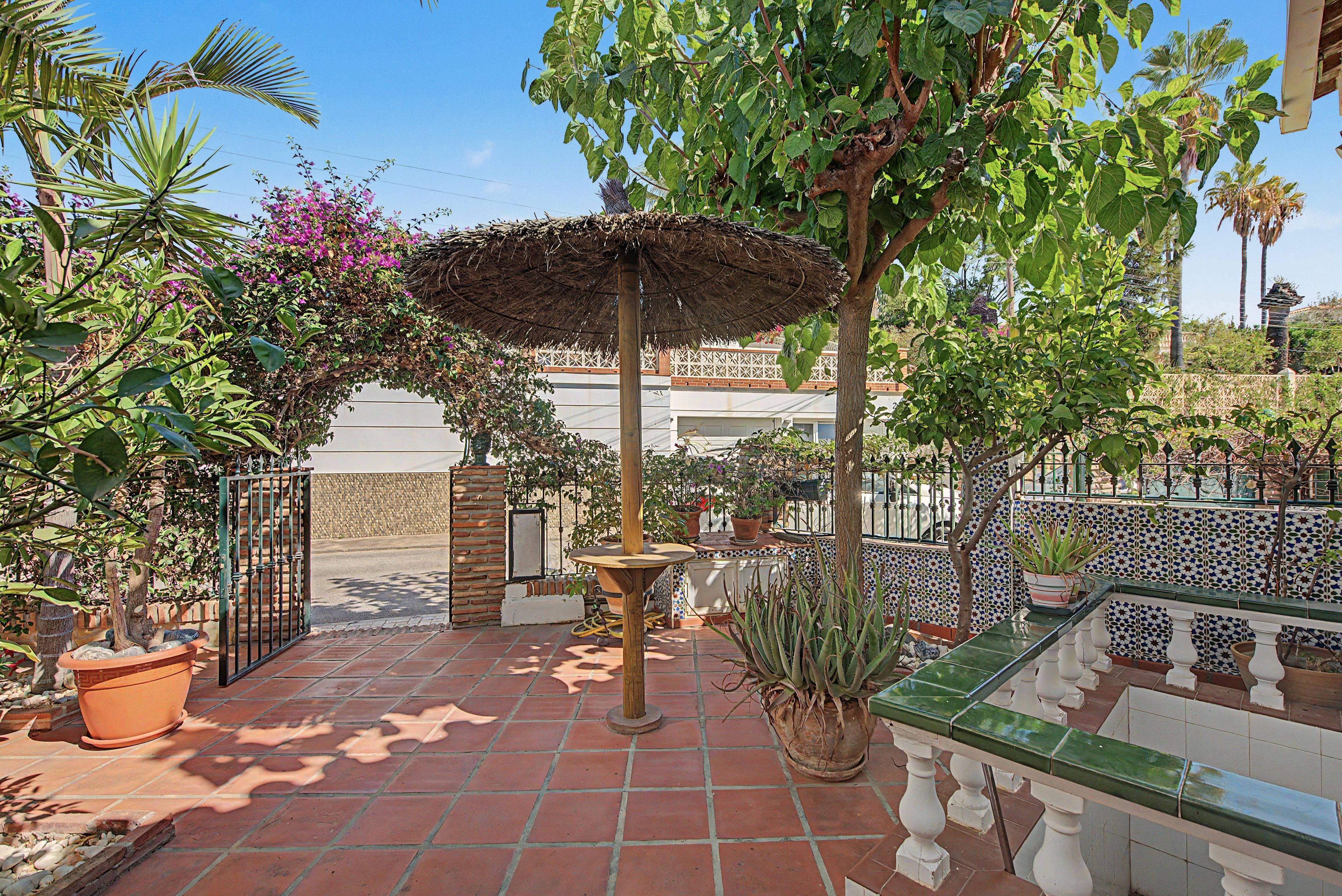 Ein Innenhof mit einer Pergola, Topfpflanzen und einem Kachelboden.