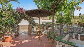 Ein Innenhof mit einer Pergola, Topfpflanzen und einem Kachelboden.