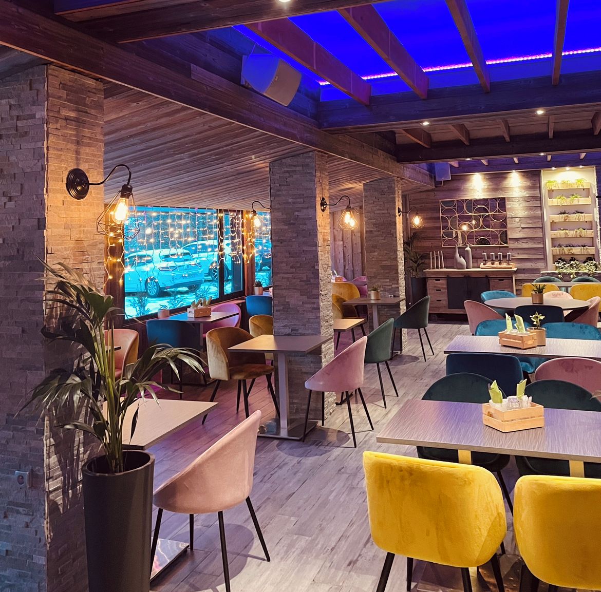 A restaurant with wooden beams, brick walls, and colorful chairs.