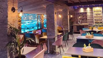 A restaurant with wooden beams, brick walls, and colorful chairs.