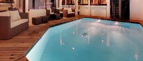 Una piscina con muelle de madera, zona de estar y escalera.