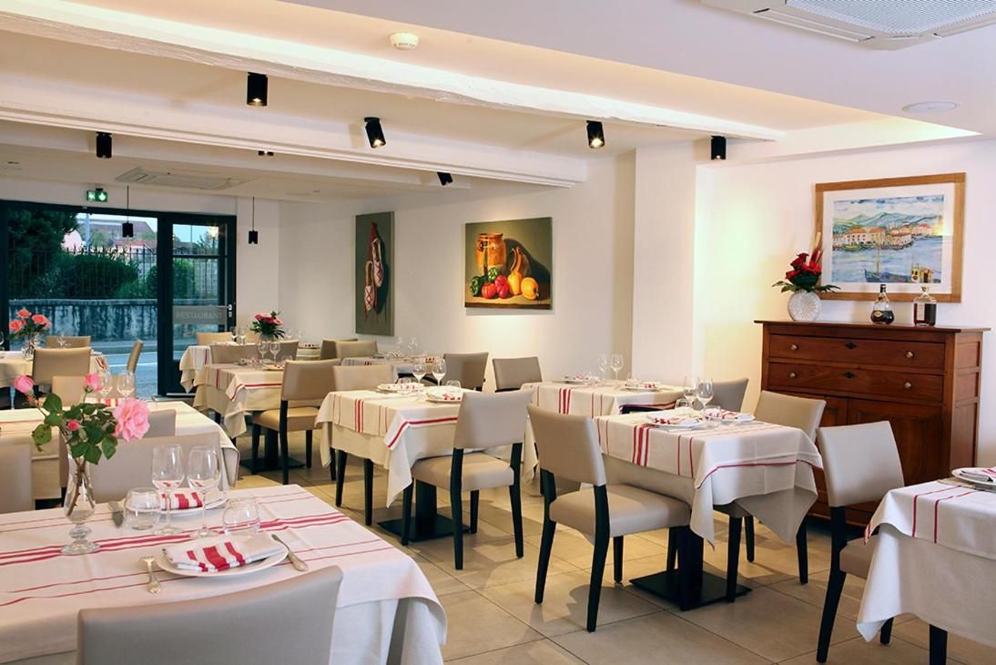 A dining area with tables set for service, chairs, and a view of the outdoors.
