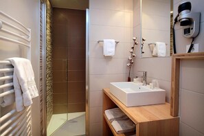 A modern bathroom with a glass shower enclosure, a white sink, and a hairdryer mounted on the wall. - Hotel De La Nivelle (Saint-Pee-sur-Nivelle)