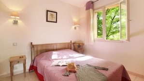 Ein Schlafzimmer mit einem Bett, Nachttischlampen, einem Fenster mit Vorhängen, einem Nachttisch und einer Wanddekoration mit einem Seestern.
