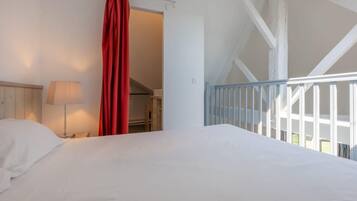 Un dormitorio con una cama, una mesita de noche, una lámpara y una cortina roja.