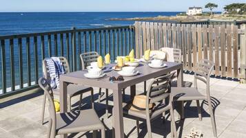 Un área de comedor al aire libre con una mesa preparada para cuatro personas, con vista al mar.