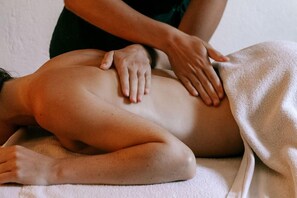 Eine Person bekommt eine Rückenmassage auf einer Massageliege.