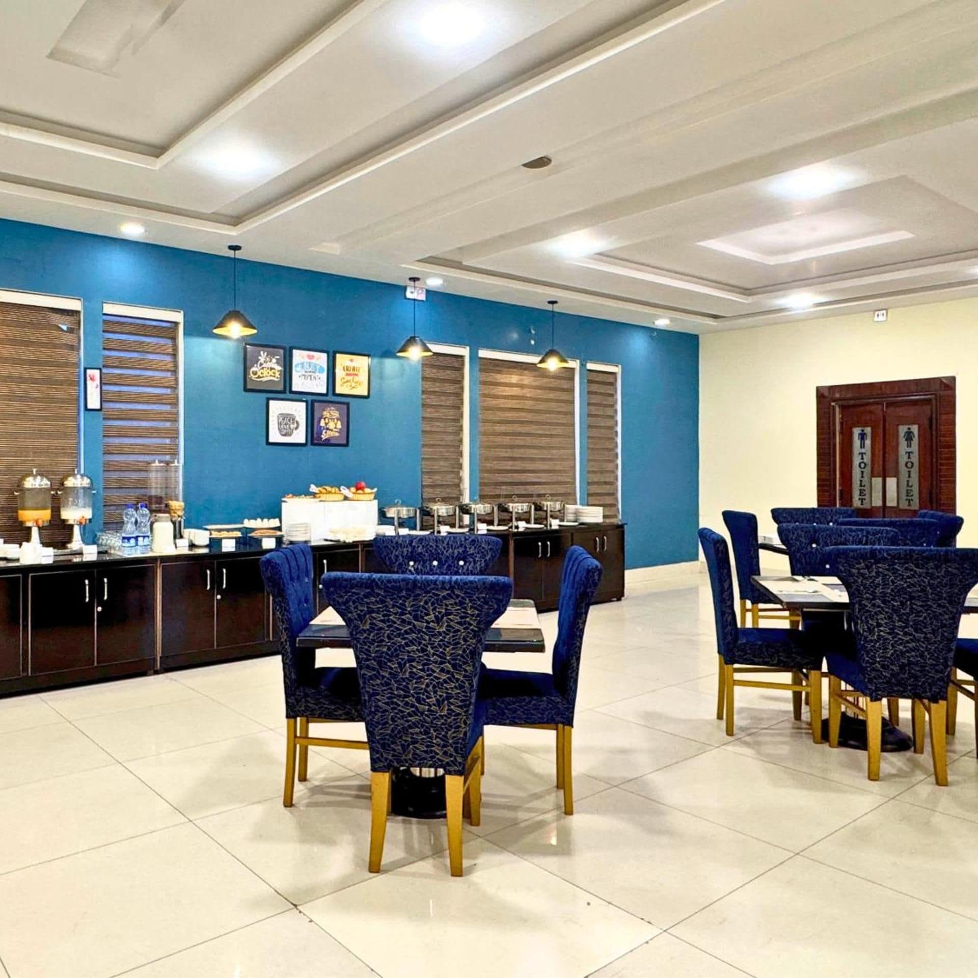 Une salle à manger d’hôtel avec des murs bleus, un buffet et plusieurs tables à manger entourées de chaises.