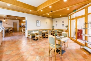 Un restaurante con mobiliario de madera, suelo de baldosas y un ambiente acogedor.