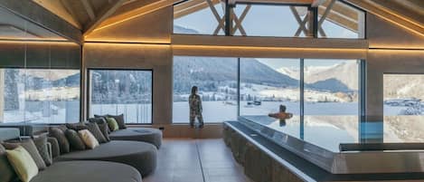 A modern interior with a large glass window overlooking a snowy landscape.