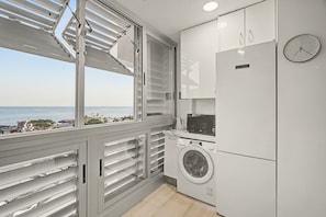 Cocina moderna con lavadora integrada, un reloj y vistas al mar.