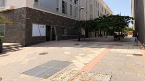 A building with a modern facade, a covered entrance, and a paved courtyard with trees and seating areas. - Vacation Apartment 'Terraza del Atlántico' with Sea View and Wi-Fi (Santa Cruz de Tenerife)