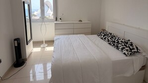 A bedroom with a bed, a dresser, a TV, and a window with a view. - Vacation Apartment 'Terraza del Atlántico' with Sea View and Wi-Fi (Santa Cruz de Tenerife)