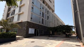 Un edificio de varios pisos con fachada plana, ventanas amplias y un patio empedrado con piso estampado.