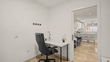A modern office space with a desk, chair, and a potted plant.