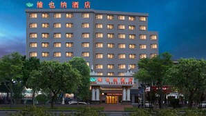 A multi-story hotel with a modern facade, illuminated windows, and a prominent entrance with signage. - Vienna Hotel Guangzhou Airport (Guangzhou)