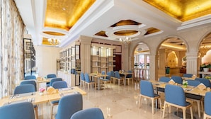 A spacious dining area with multiple tables and chairs, a high ceiling with decorative lighting, and a view of the street outside. - Vienna Hotel Guangzhou Airport (Guangzhou)