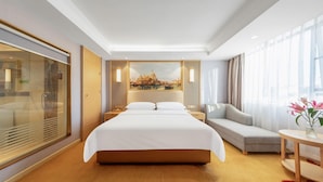 A hotel room with a large bed, a sofa, a desk, and a large window with curtains. - Vienna Hotel Guangzhou Airport (Guangzhou)