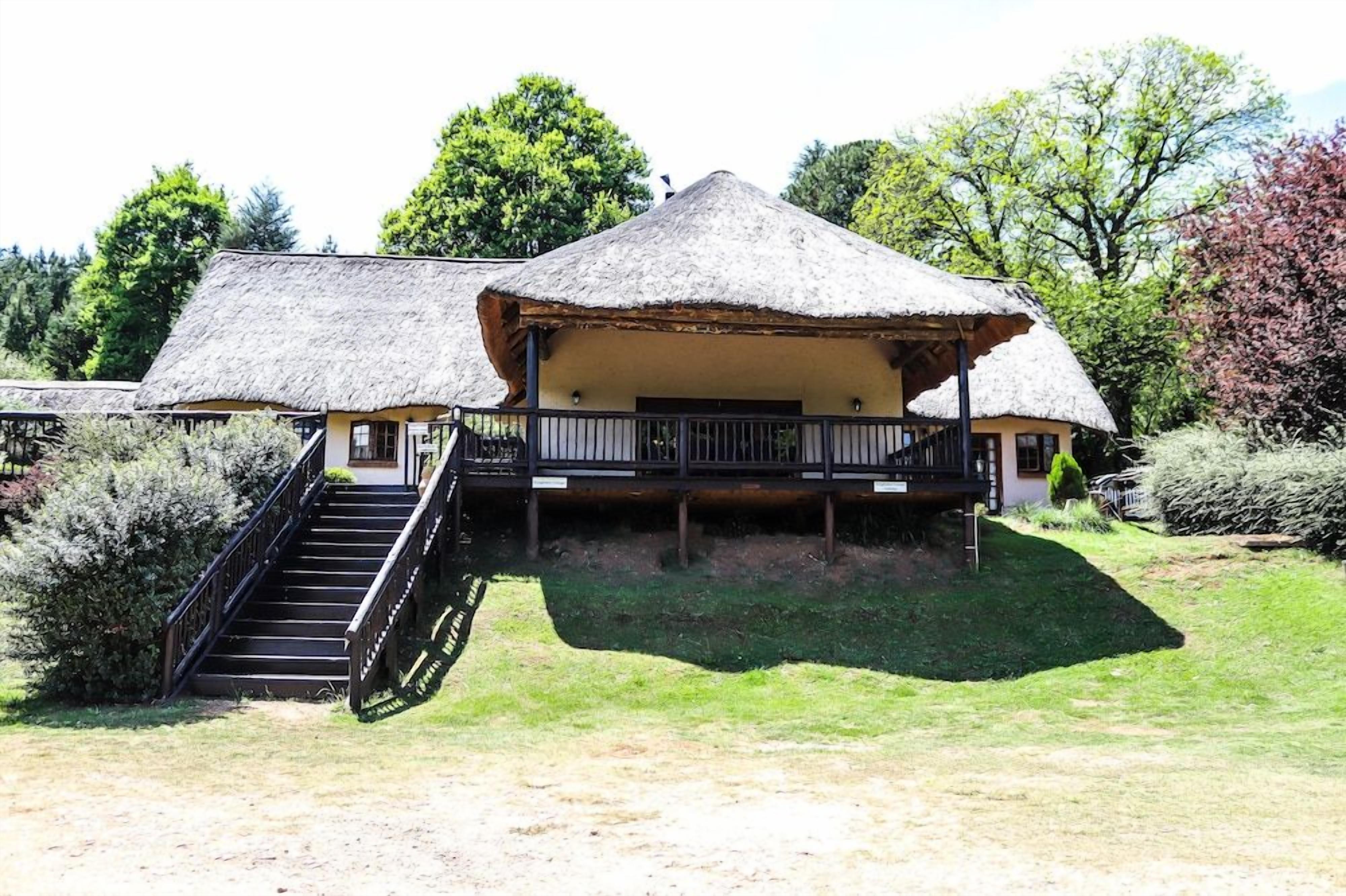 A thatched-roof building with a staircase leading to a covered porch.