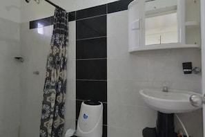 A bathroom with a shower, a sink, and a cabinet. - Apartamentos Hermanos Morales Merino (San Andrés)