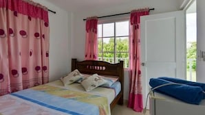 Une chambre avec un lit simple, une fenêtre avec des rideaux et une porte.