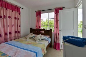 A bedroom with a single bed, a window with curtains, and a door. - Apartamentos Hermanos Morales Merino (San Andrés)