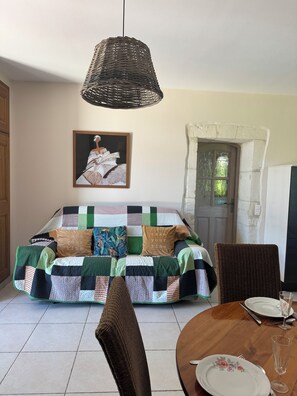 A cozy room with a sofa, a dining table, and a hanging light fixture. - At YVETTE's (Saint-Rémy-de-Provence)