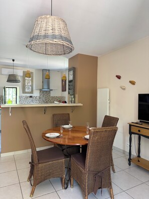 A dining area with wicker chairs, a round wooden table, and hanging pendant lights. - At YVETTE's (Saint-Rémy-de-Provence)