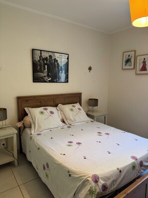 A bedroom with a bed, nightstands, a wooden headboard, a framed picture on the wall, and a lamp on each nightstand. - At YVETTE's (Saint-Rémy-de-Provence)