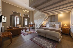 Un dormitorio espacioso con una cama grande, una chimenea, una escalera y una zona de estar acogedora.