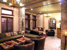 A cozy lounge area with a stone wall, a fireplace, and comfortable seating.