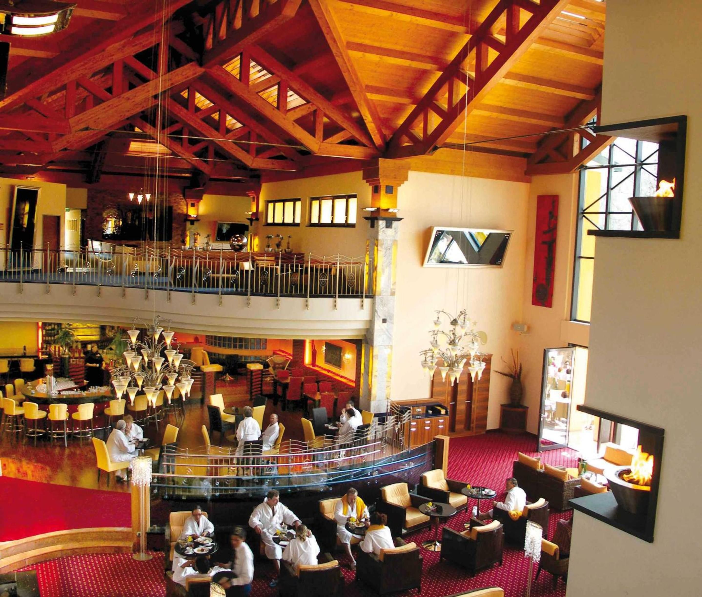 A spacious hotel lobby with a high ceiling, multiple seating areas, and a bar.