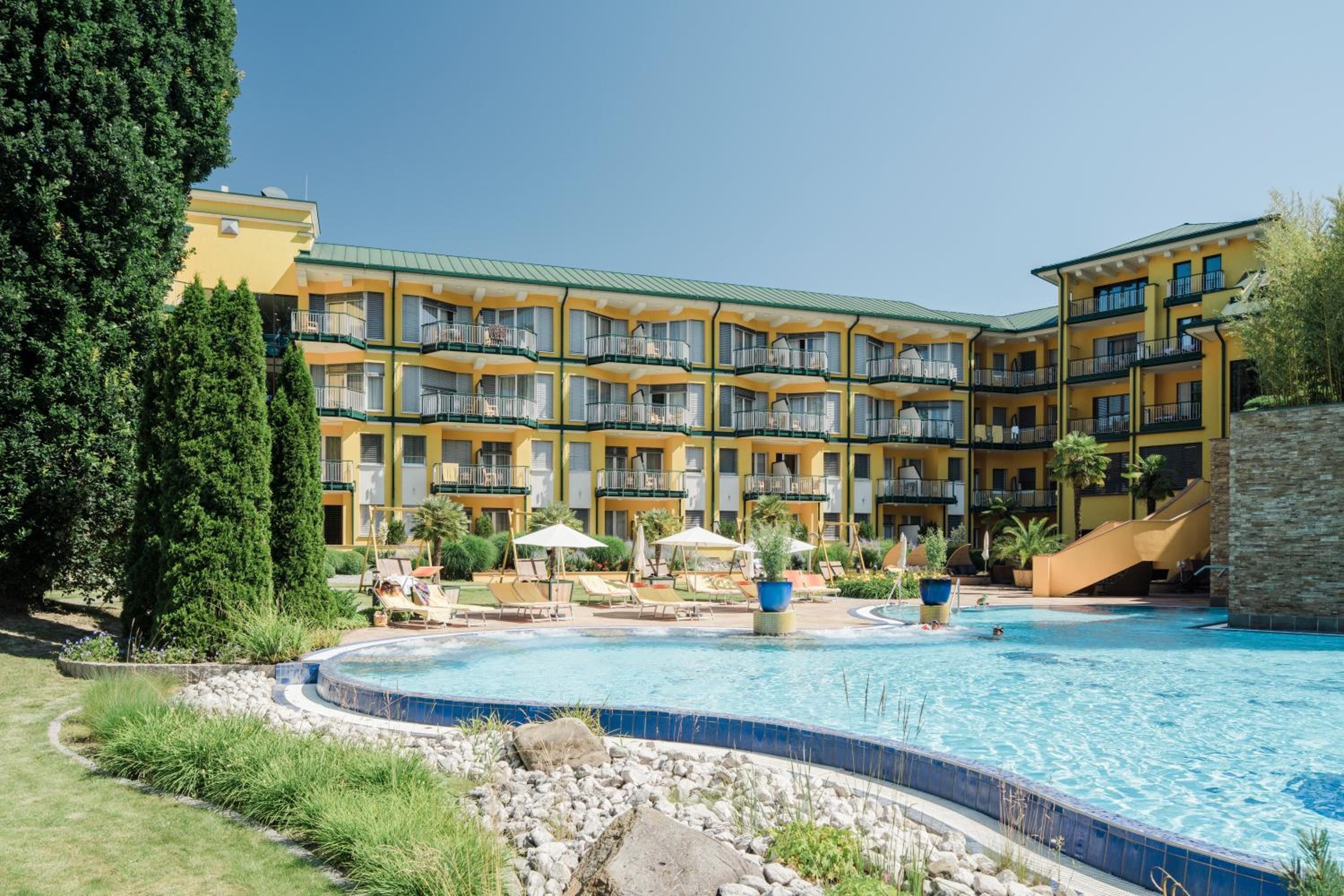 A hotel with a pool, multiple balconies, and a landscaped garden.