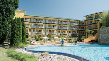 A hotel with a pool, multiple balconies, and a landscaped garden.