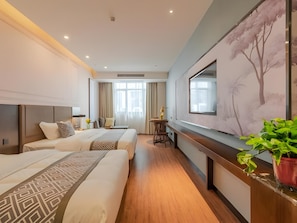 Habitación de hotel con dos camas, un escritorio, una silla, un ventanal grande y un cuadro en la pared.