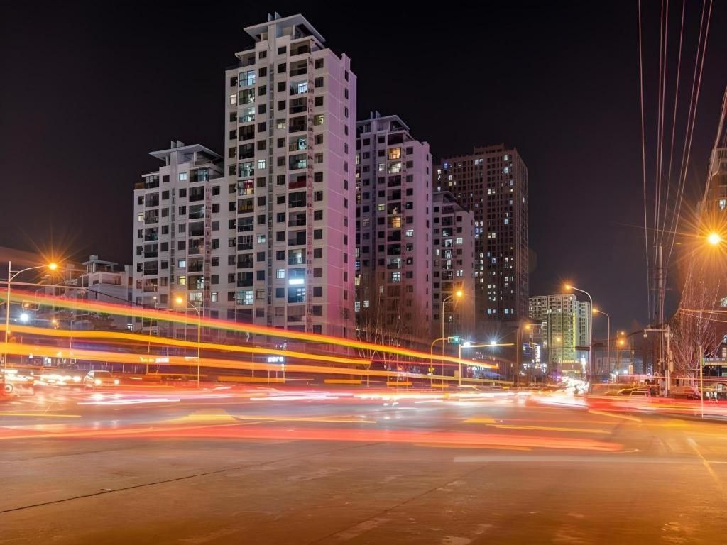 A nighttime cityscape with high-rise buildings and light trails from moving vehicles.