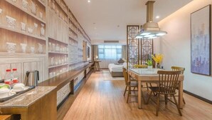 A modern kitchen with wooden shelves, a dining area with a table and chairs, and a large window providing natural light. - Gem Hefei Qianshan North Road Phoenix Hotel (Hefei)