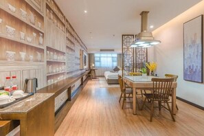 Una cocina moderna con estantes de madera, un comedor con mesa y sillas, y un amplio ventanal que proporciona luz natural.