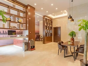 Un moderno vestíbulo de hotel con mostrador de recepción, zona de estar y una amplia estantería.