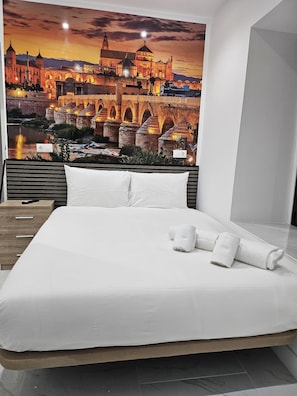 A hotel room with a large bed, a view of a historic building, and a night sky. - PENSION CIBELES (Córdoba)