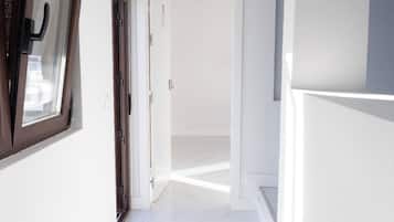 A hallway with a marble floor, a door on the left, and a staircase on the right.