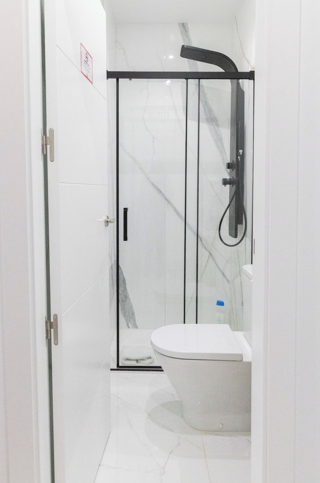 Un bany modern amb una cabina de dutxa de vidre, una banyera independent i un vàter.