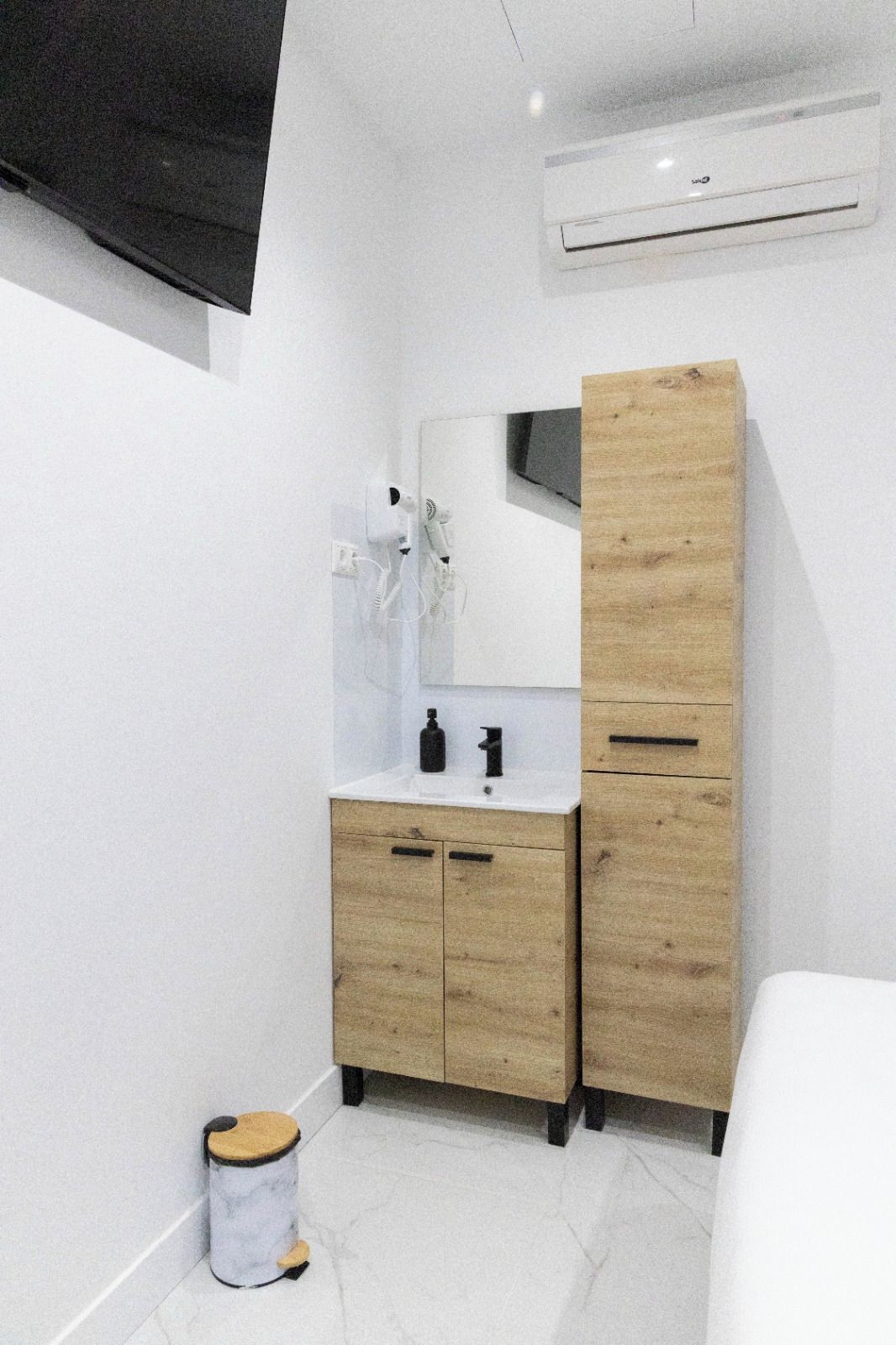 Een moderne badkamer met een houten wastafelmeubel, een spiegel en een witte wasbak.